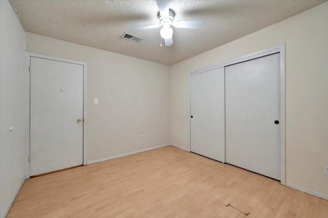 unfurnished bedroom with visible vents, baseboards, wood finished floors, a closet, and a textured ceiling