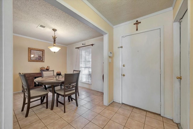 dining space featuring visible vents, a textured ceiling, ornamental molding, and light tile patterned flooring