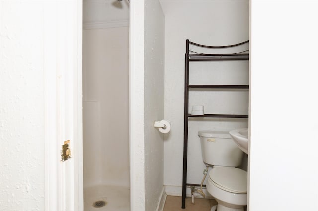 bathroom featuring a shower stall, toilet, and baseboards