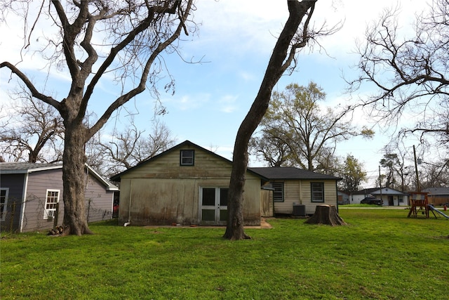 rear view of house with a lawn, central AC unit, and a playground