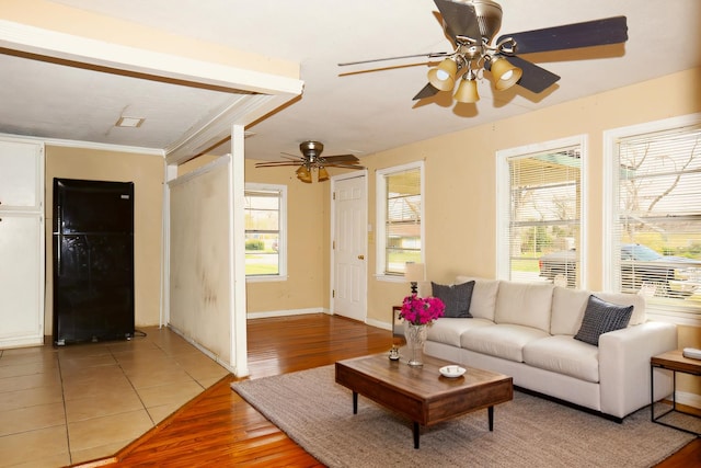 living area featuring light wood-style flooring, baseboards, and ceiling fan