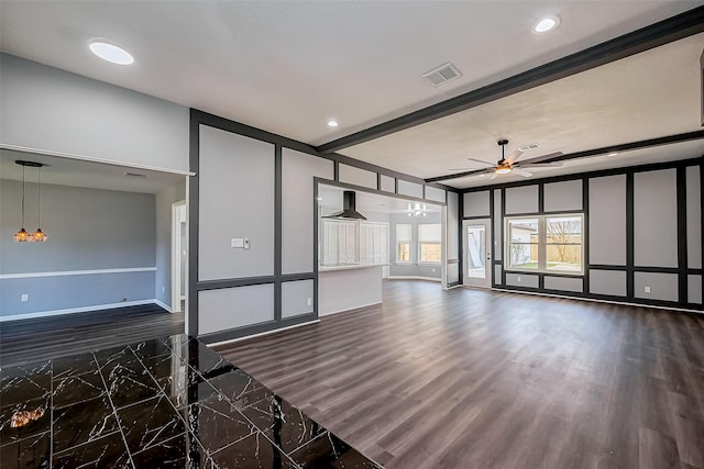 unfurnished living room featuring beamed ceiling, visible vents, ceiling fan with notable chandelier, dark wood-style floors, and a decorative wall