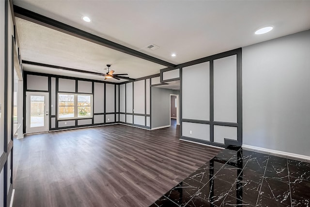 spare room featuring visible vents, dark wood-style flooring, ceiling fan, beamed ceiling, and a decorative wall