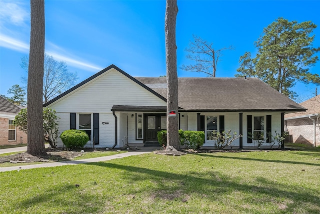 view of front of house featuring brick siding, a porch, a front lawn, and roof with shingles