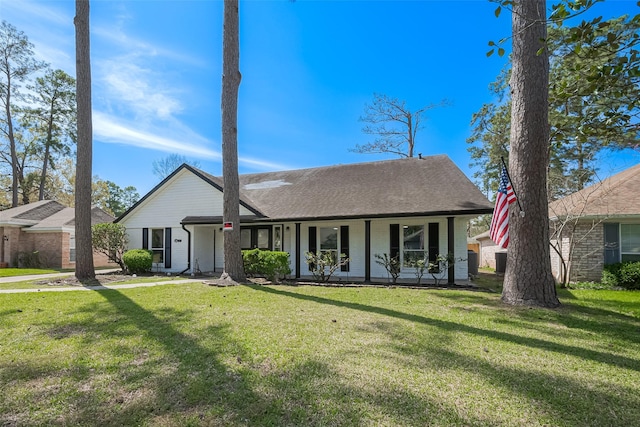 view of front facade featuring a front yard, a porch, brick siding, and roof with shingles