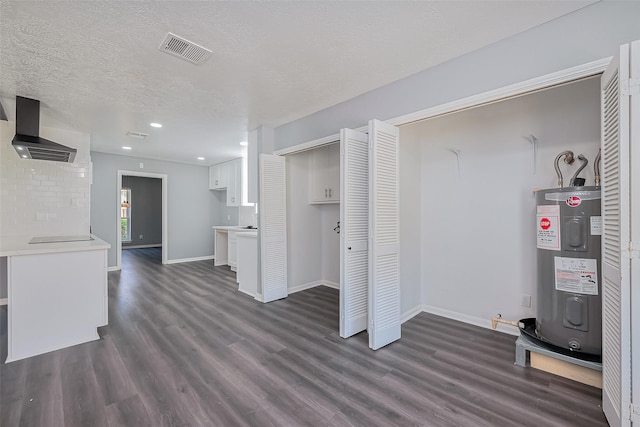 unfurnished living room featuring visible vents, baseboards, electric water heater, and dark wood-style floors