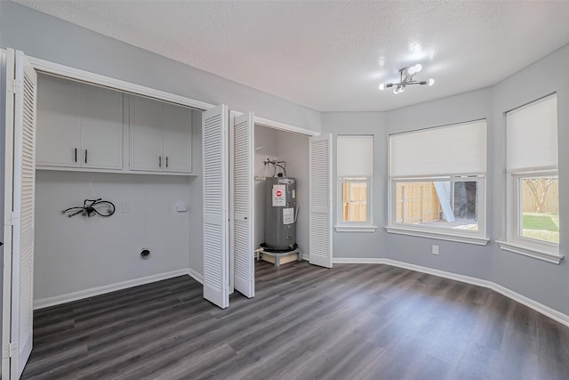 washroom with dark wood finished floors, cabinet space, baseboards, and electric water heater