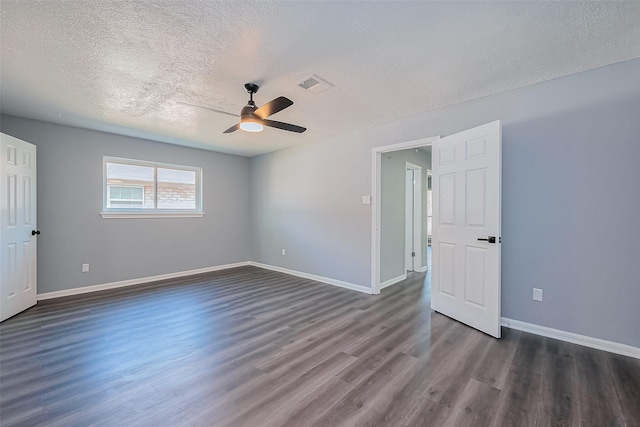 spare room featuring baseboards, visible vents, dark wood-style flooring, ceiling fan, and a textured ceiling