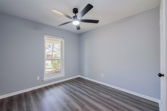 spare room featuring baseboards, dark wood-type flooring, and a ceiling fan