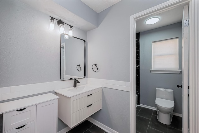 full bath featuring toilet, vanity, and tile patterned flooring