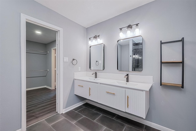 bathroom featuring tile patterned floors, double vanity, baseboards, and a sink