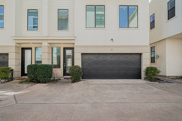 townhome / multi-family property featuring concrete driveway, an attached garage, and stucco siding