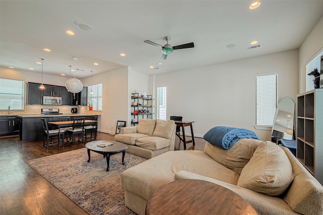 living area with visible vents, dark wood-type flooring, a healthy amount of sunlight, and ceiling fan