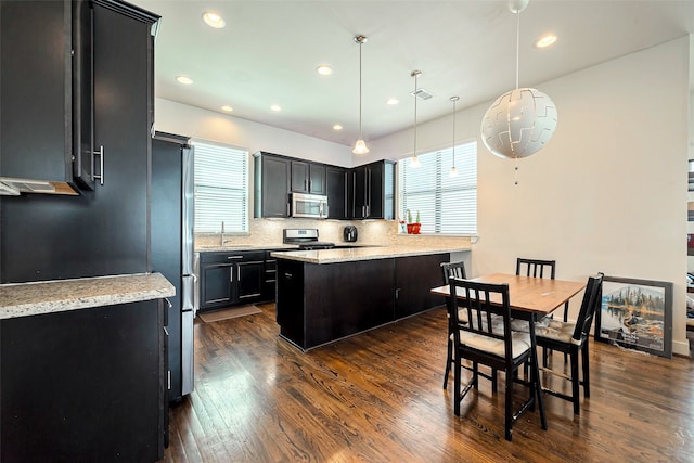 kitchen with plenty of natural light, stainless steel appliances, dark cabinetry, and dark wood-style flooring