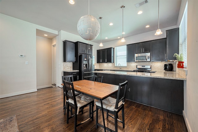 kitchen with visible vents, dark wood finished floors, decorative backsplash, stainless steel appliances, and a sink