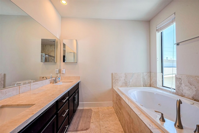 bathroom with double vanity, a jetted tub, baseboards, and a sink