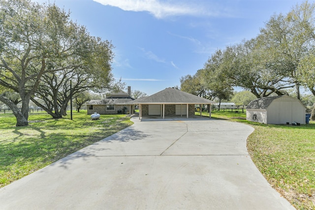 view of front of home with driveway, an outbuilding, a front lawn, and a shed