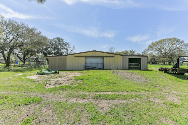 view of pole building with a lawn, fence, and dirt driveway