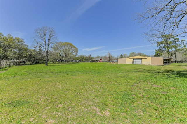 view of yard with a garage, an outbuilding, and fence