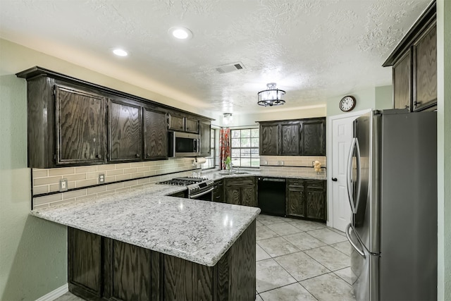 kitchen with visible vents, a sink, tasteful backsplash, stainless steel appliances, and a peninsula