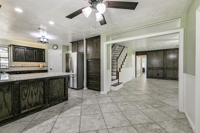 kitchen with backsplash, light stone counters, freestanding refrigerator, light tile patterned flooring, and a textured ceiling