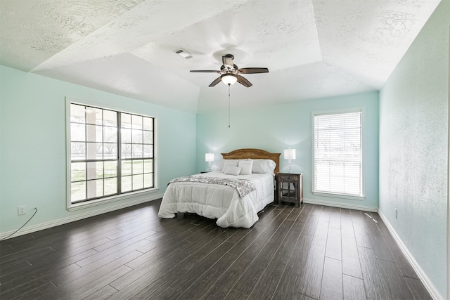 bedroom with visible vents, a textured ceiling, dark wood-type flooring, and baseboards