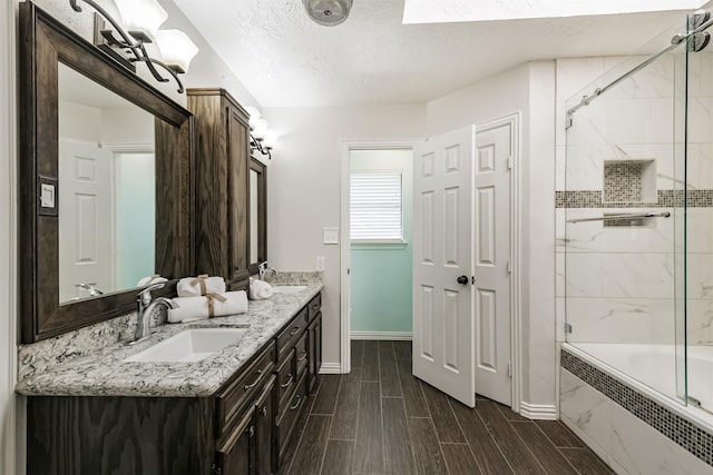 full bathroom featuring baseboards, wood finish floors, a sink, a textured ceiling, and shower / bathing tub combination