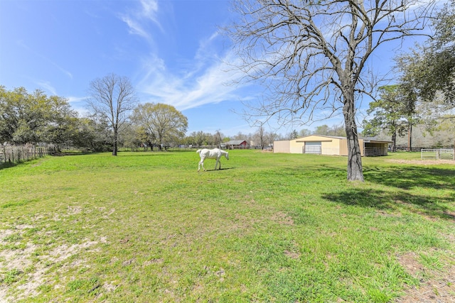 view of yard featuring a rural view, an outbuilding, fence, and a detached garage