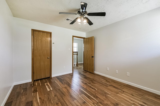 unfurnished bedroom featuring visible vents, baseboards, wood finished floors, a textured ceiling, and a ceiling fan