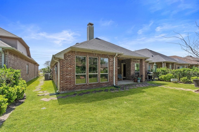 back of house featuring a patio, a lawn, brick siding, and central AC