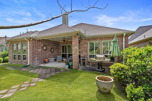 rear view of house with brick siding, a yard, and ceiling fan