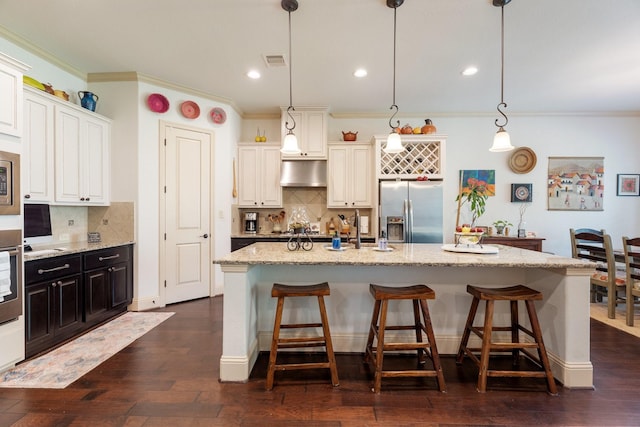 kitchen with visible vents, dark wood-type flooring, stainless steel fridge with ice dispenser, under cabinet range hood, and a sink