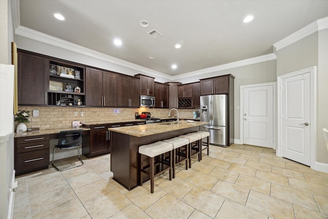 kitchen with light stone counters, decorative backsplash, appliances with stainless steel finishes, a kitchen breakfast bar, and a sink