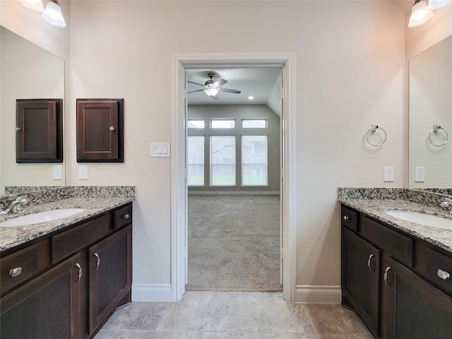 bathroom with a sink, baseboards, two vanities, and a ceiling fan