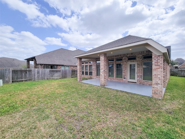 rear view of property featuring a patio area, a yard, a fenced backyard, and brick siding