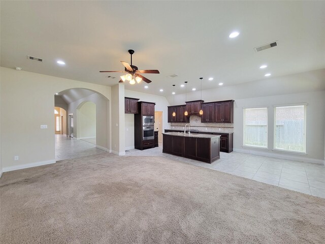 living area with arched walkways, visible vents, light colored carpet, and ceiling fan