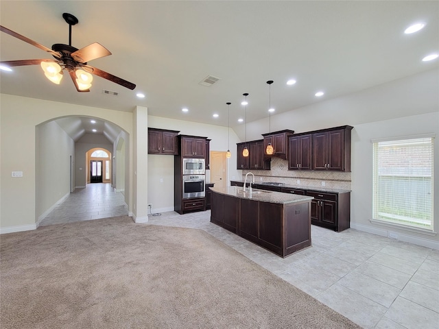 kitchen with dark brown cabinets, visible vents, arched walkways, and appliances with stainless steel finishes