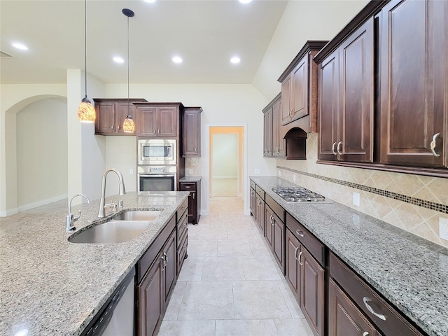 kitchen with light stone countertops, decorative light fixtures, decorative backsplash, stainless steel appliances, and a sink