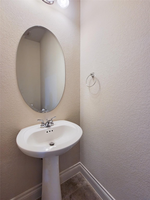 bathroom featuring tile patterned flooring, baseboards, and a textured wall