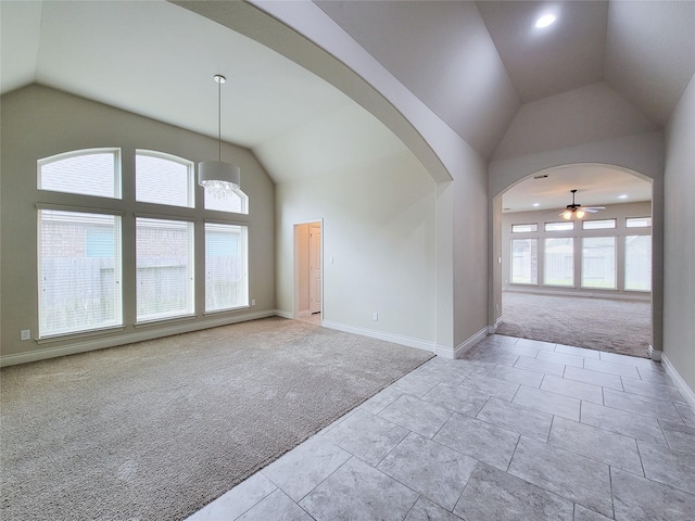 carpeted spare room featuring baseboards, a healthy amount of sunlight, arched walkways, and ceiling fan