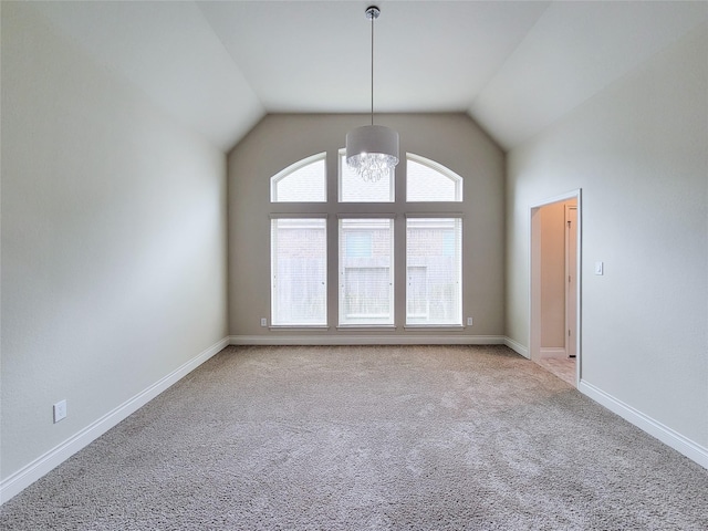 spare room featuring light carpet, a notable chandelier, lofted ceiling, and baseboards