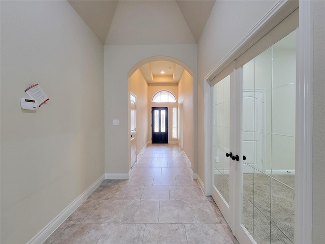 hall with arched walkways, light tile patterned floors, french doors, and baseboards