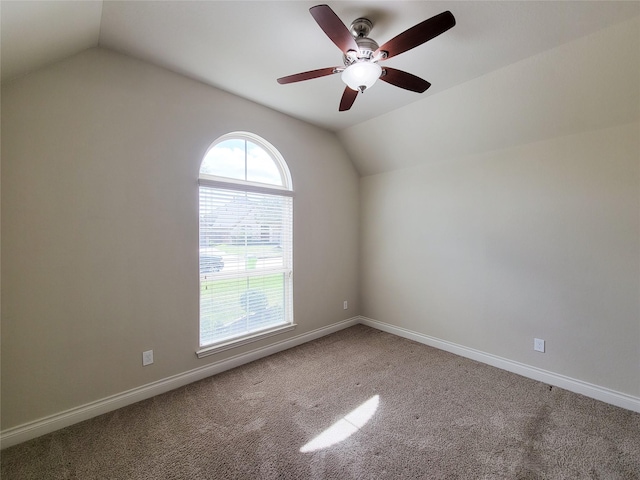 empty room featuring baseboards, carpet, ceiling fan, and vaulted ceiling