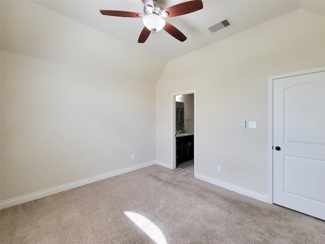 spare room featuring visible vents, light carpet, lofted ceiling, baseboards, and ceiling fan