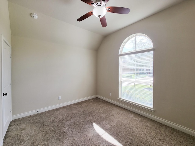 spare room with lofted ceiling, carpet flooring, a ceiling fan, and baseboards