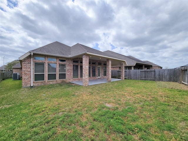 rear view of property featuring a patio, a fenced backyard, central AC, a lawn, and brick siding