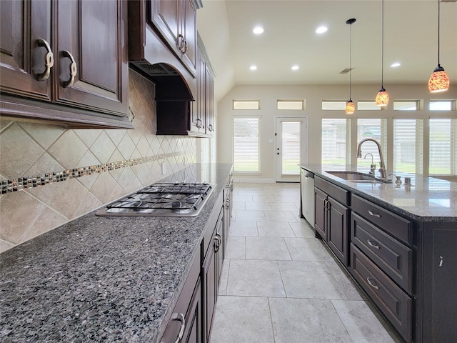 kitchen featuring a sink, under cabinet range hood, tasteful backsplash, stainless steel appliances, and dark stone counters