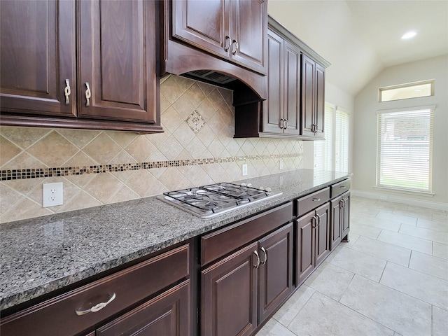 kitchen featuring stainless steel gas cooktop, under cabinet range hood, vaulted ceiling, light tile patterned floors, and stone counters