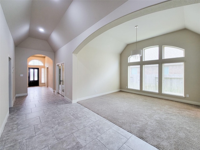 empty room with high vaulted ceiling, baseboards, arched walkways, and light carpet