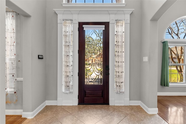 tiled foyer featuring baseboards and plenty of natural light